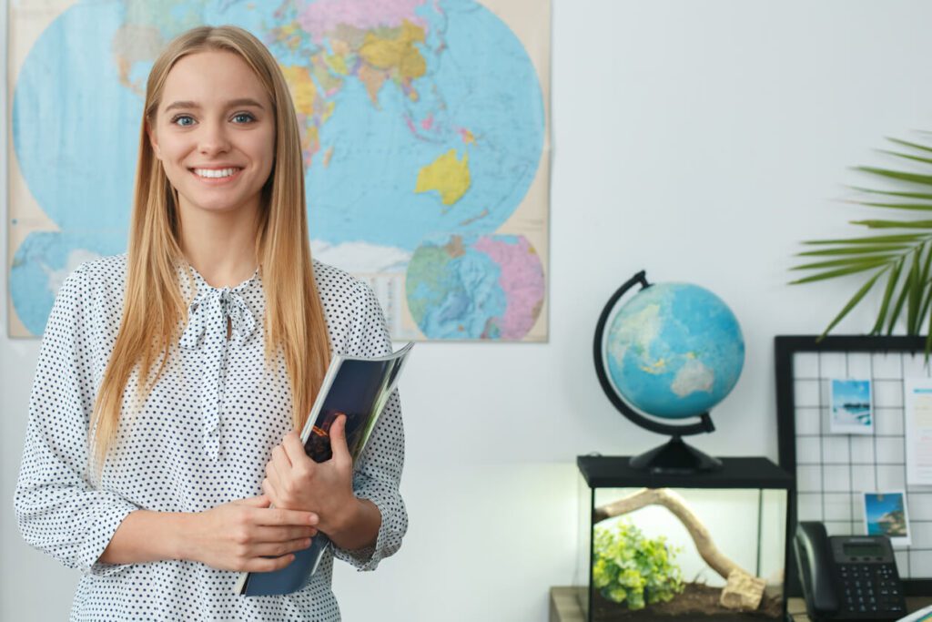 Woman tour operator stood in front of a world map ready to book a trip