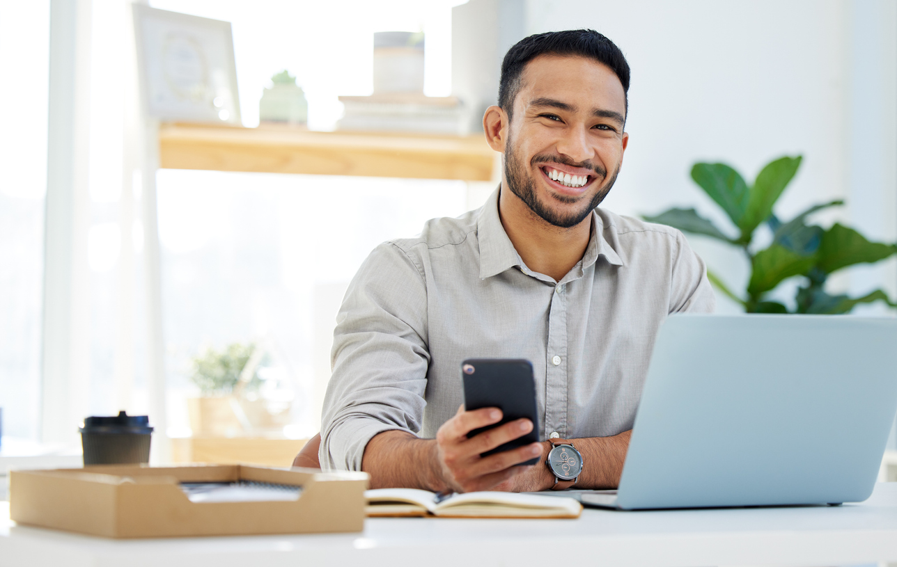 Smiling travel agent working on laptop and phone, offering business travel booking services online
