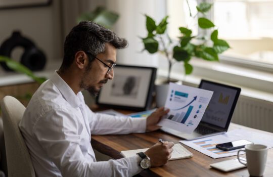 Travel agent analyzing financial reports and charts using accounting software on a laptop