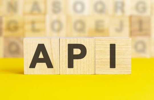 Wooden blocks spelling API on a yellow background, symbolizing Expedia API integration for travel booking, hotel search, and online reservation systems