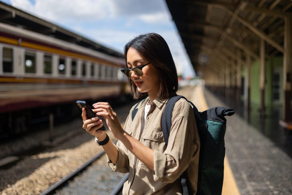 Female tourist relying on mobile travel technology during train journey.